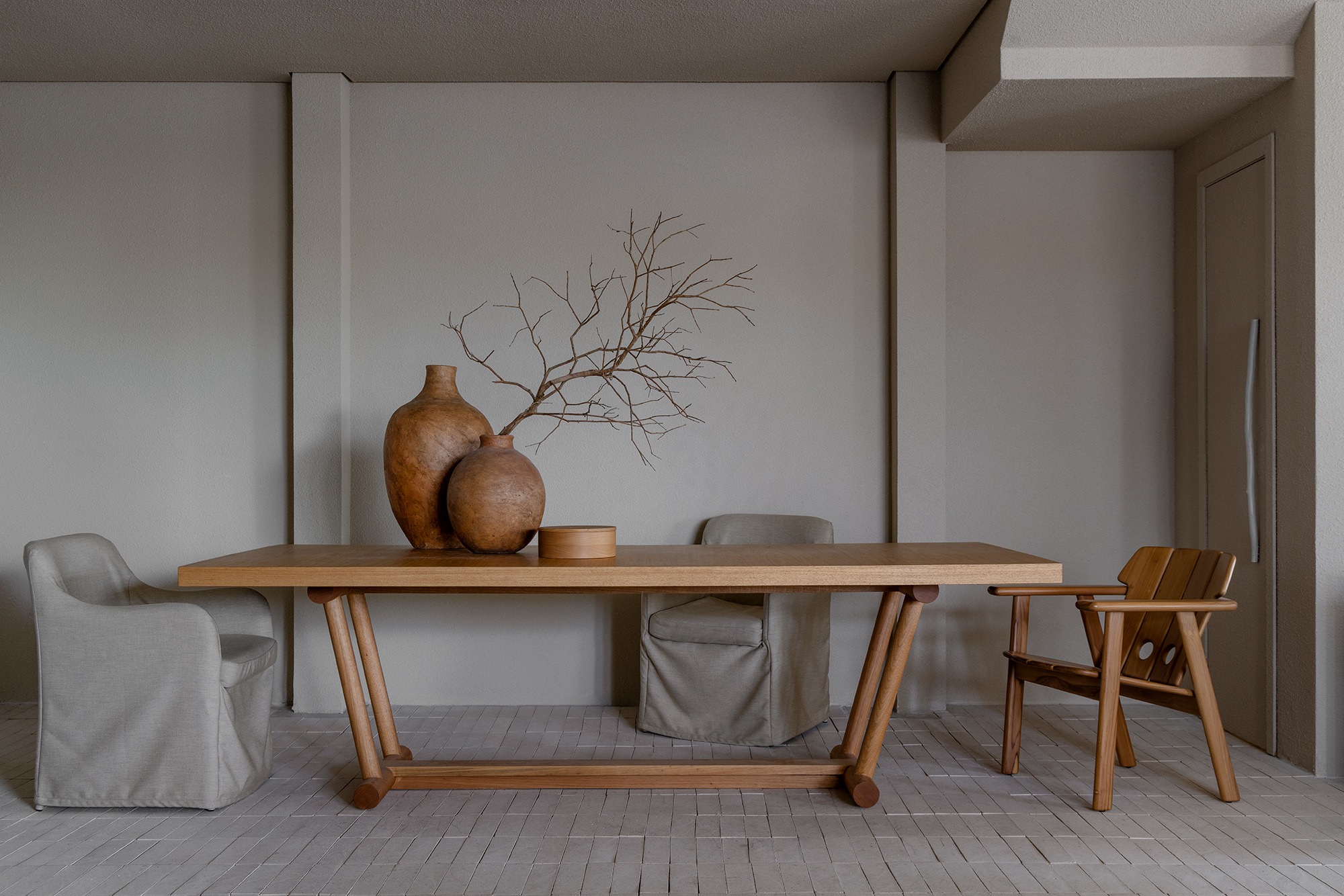 Sala de jantar em tons naturais com mesa de madeira e mobiliário da curadoria